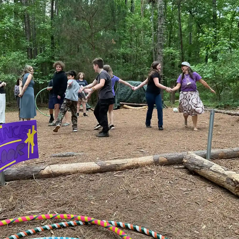 Students dancing together on a woodland trail