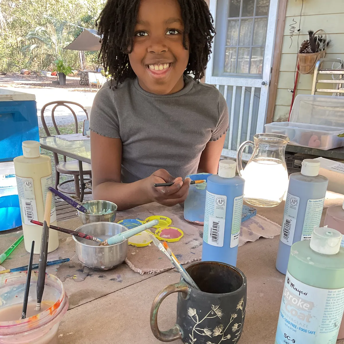 A student glazing a handmade pottery mug
