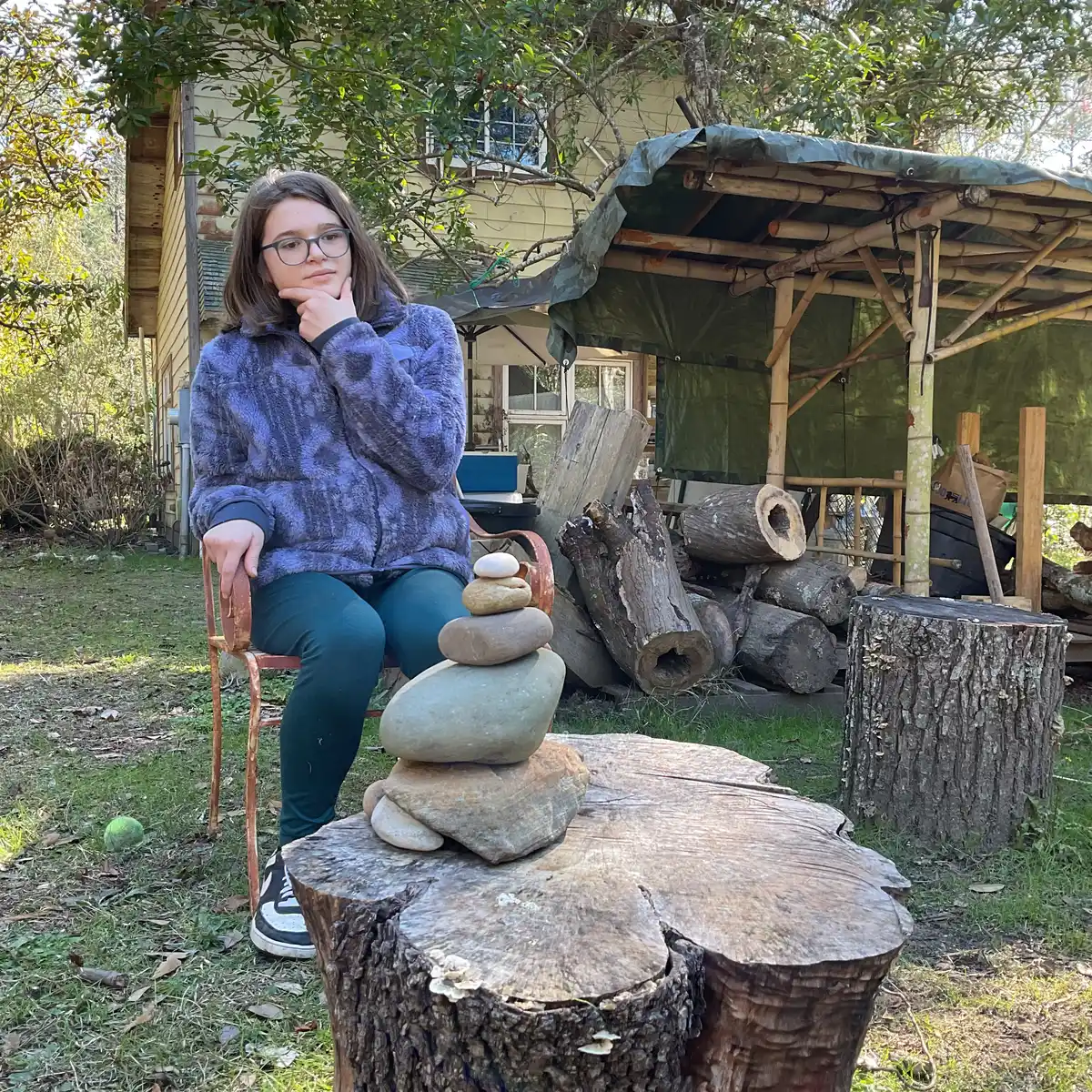 A student balancing a stone cairn on an old tree stump
