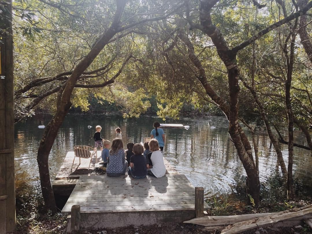 Children sitting together on a wooden dock at the pond